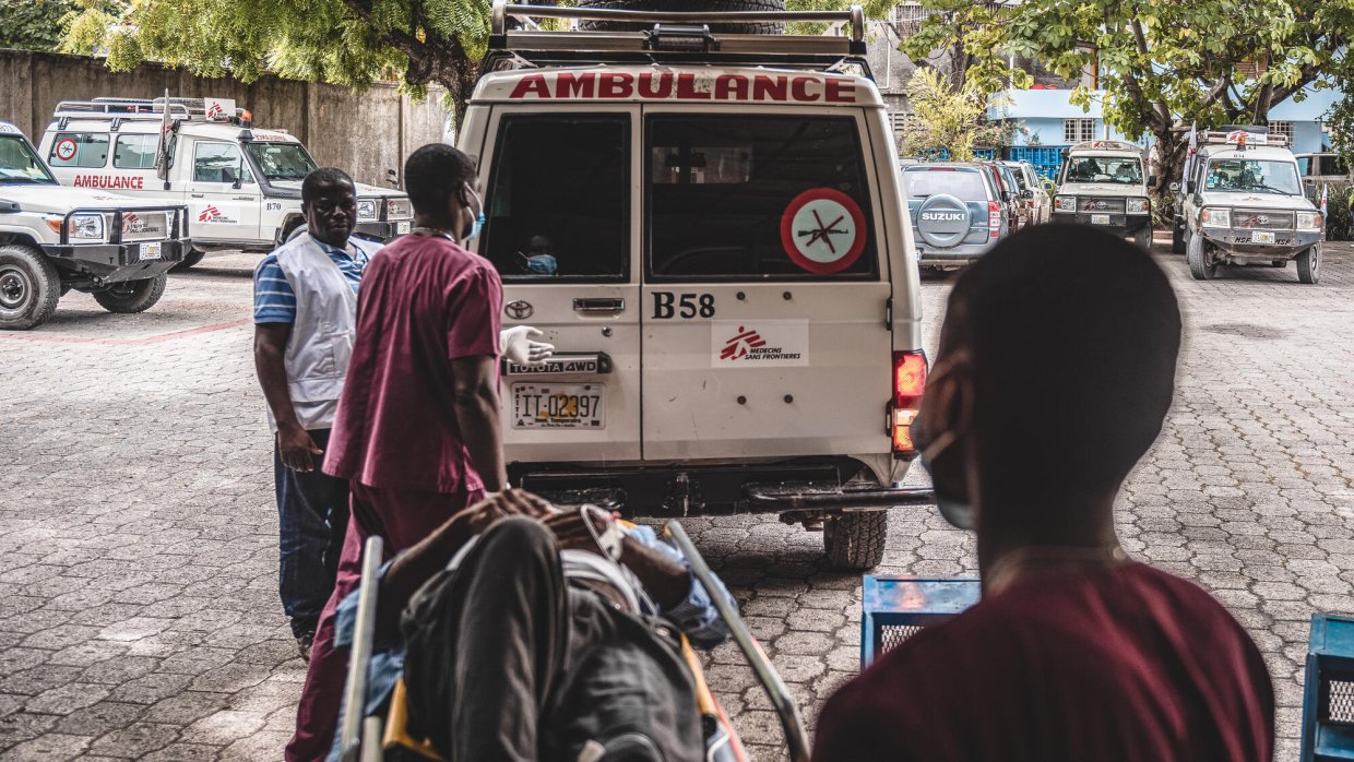En man på bår bärs in i Läkare Utan Gränsers ambulans.