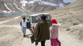 en vit jeep och tre personer på en bergsväg i Afghanistan