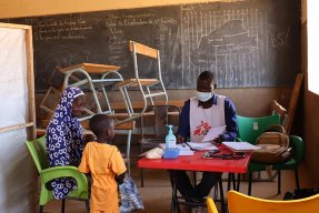 En pojke, som står bredvid sin mamma, träffar personal från Läkare Utan Gränser på en mobil klinik i Titao, Burkina Faso. 