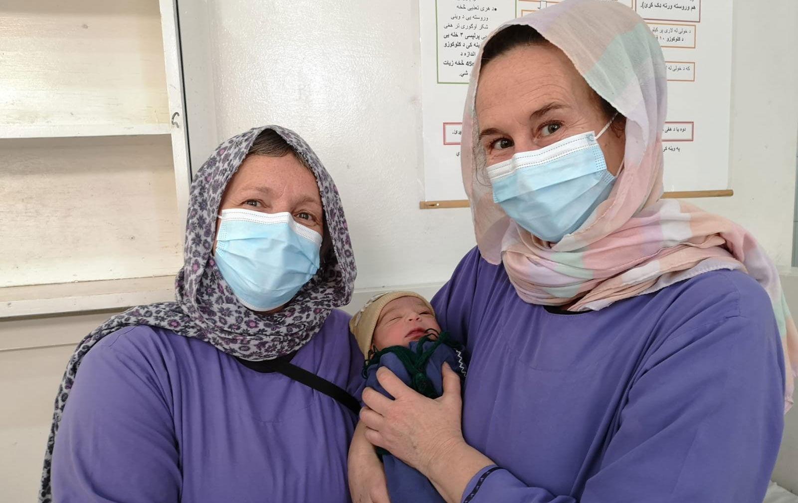 Barnmorskorna Astrid och Lena håller i en nyfödd bebis, på Khost kvinnorsjukhus i Afganistan.