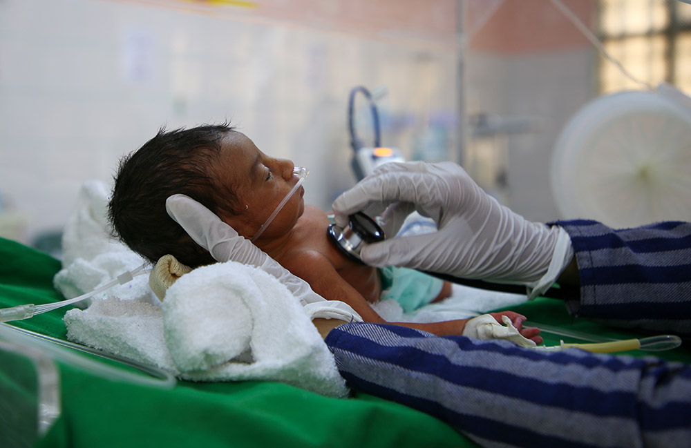Sjukvårdspersonal lyssnar med stetoskop på en liten bebis på al Jamhouri sjukhus i Taiz City, Jemen.
