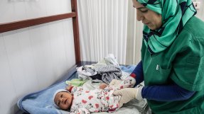 En barnmorska undersöker en nyfödd bebis på ett sjukhus i Irak.
