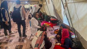I ett tält sitter ett par kvinnor på golvet. Bredvid står Läkare Utan Gränsers personal på huk.