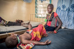 En flicka som blivit ormbiten ligger på en brits på ett sjukhus i Kenya, hennes mamma sitter bredvid och tittar in i kameran. 