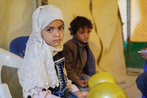 Sjuåriga Asifa sitter på en bänk, bakom henne sitter lillebror Wardan. De bor i ett flyktingläger i Marib, Jemen.