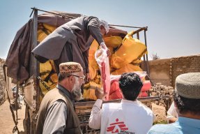 En man lastar förnödenheter från en lastbil till väntande i Pakistan