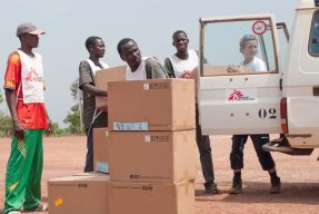 En team med logistiker lastar in papplådor i en vit bil. 