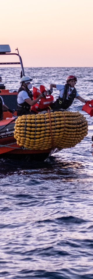 En gummibåt från Läkare Utan Gränsers sök- och räddningsfartyg Geo Barents undsätter en grupp människor från en träbåt på centrala Medelhavet.