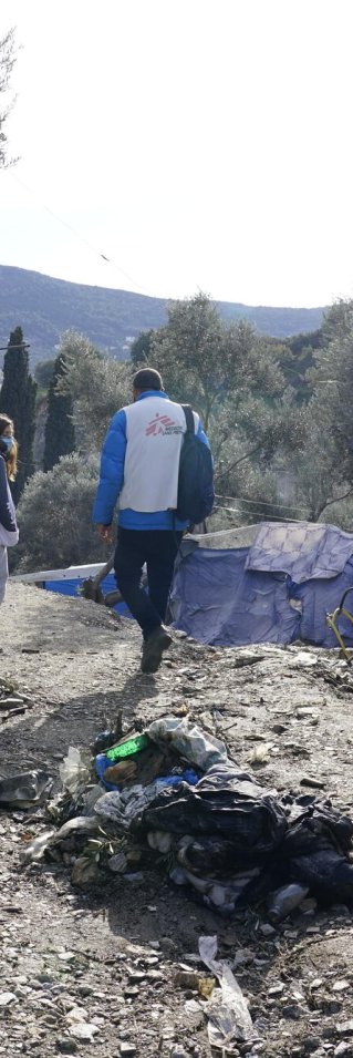 Två personer med Läkare Utan Gränser väst går mellan några tillfälliga tält av presseningar.